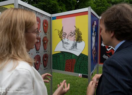 fotografia. art piknik w willi decjusza. plenerowa wystawa plakatów teatralnych. dwoje ludzi przed plakatem.